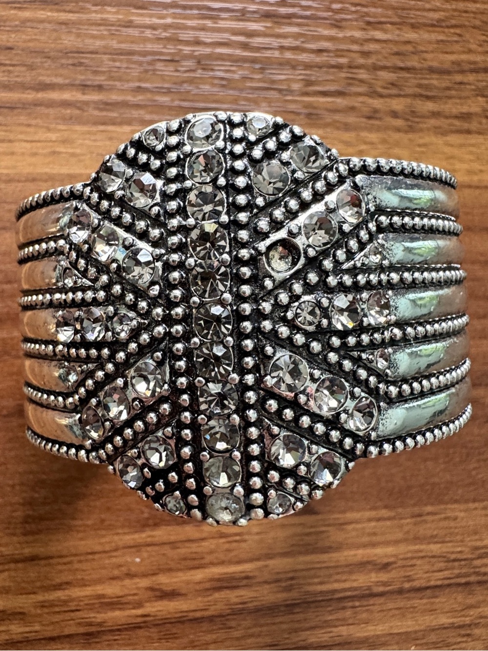Silver-toned cuff bracelet featuring a detailed flower design with crystals